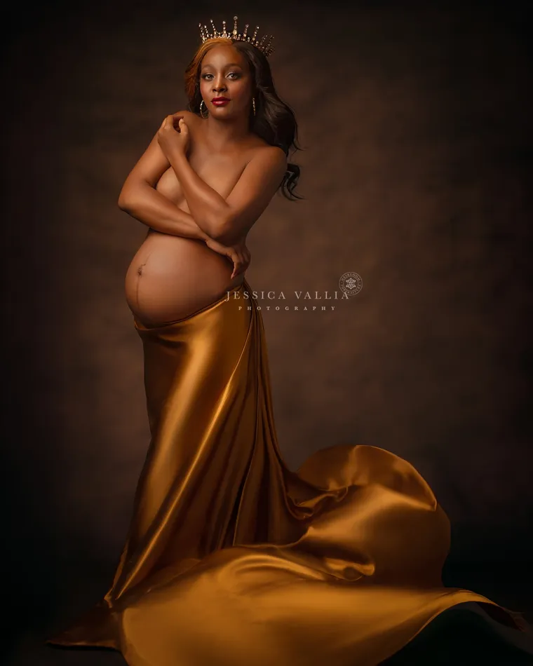 Fine art maternity portrait in a gold satin drape and crown